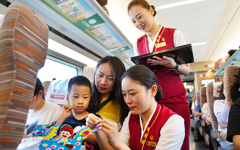 6月22日，g305次列车乘务人员帮助小旅客制作龙舟手工。刘超摄