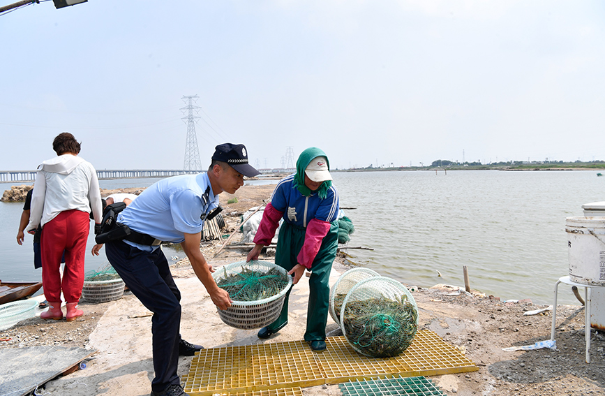 沿海安全保卫总队民警在帮助群众抢收鱼获。天津市公安局供图