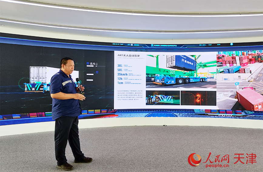 天津港第二集装箱码头公司副总经理高延辉为调研采访团介绍art无人自动驾驶。人民网 郭维瑾摄